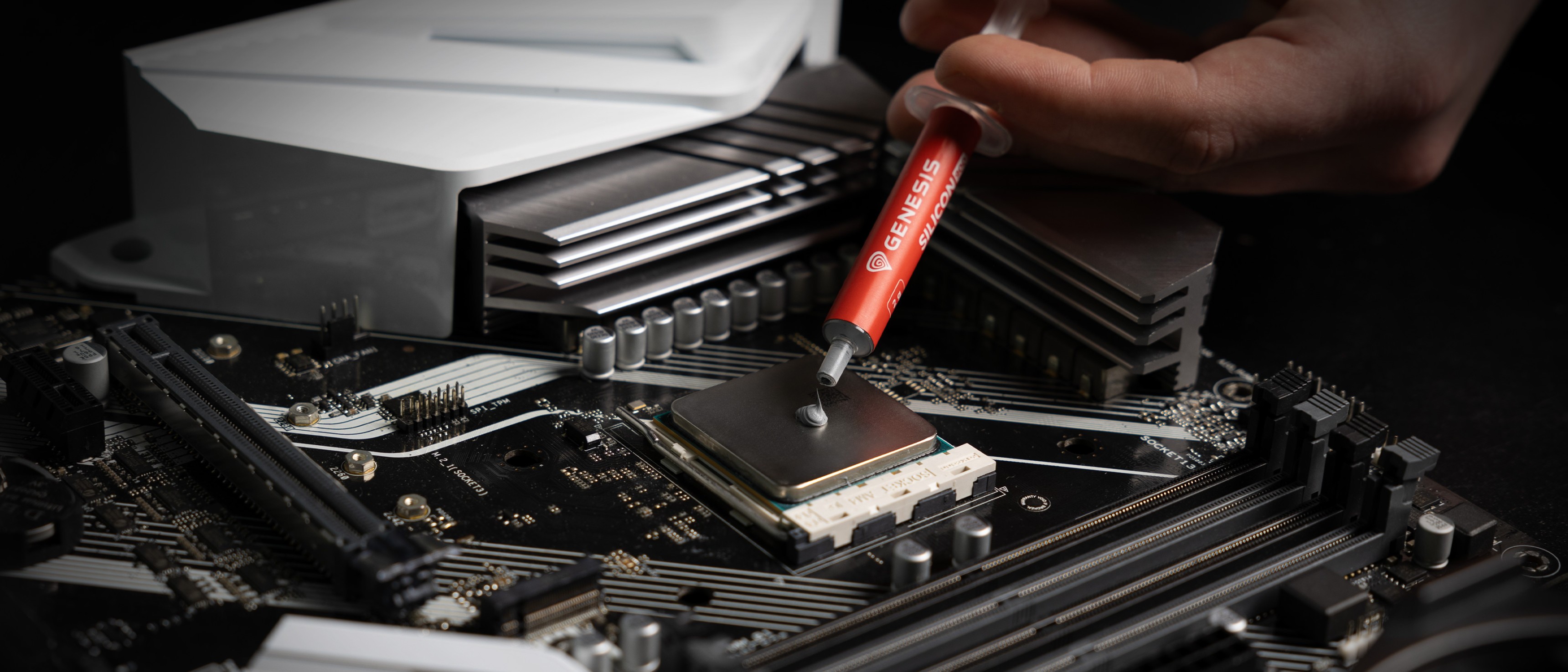 Pasta térmica aplicada con una jeringuilla en el zócalo de la CPU de una placa base, con los componentes de refrigeración a la vista