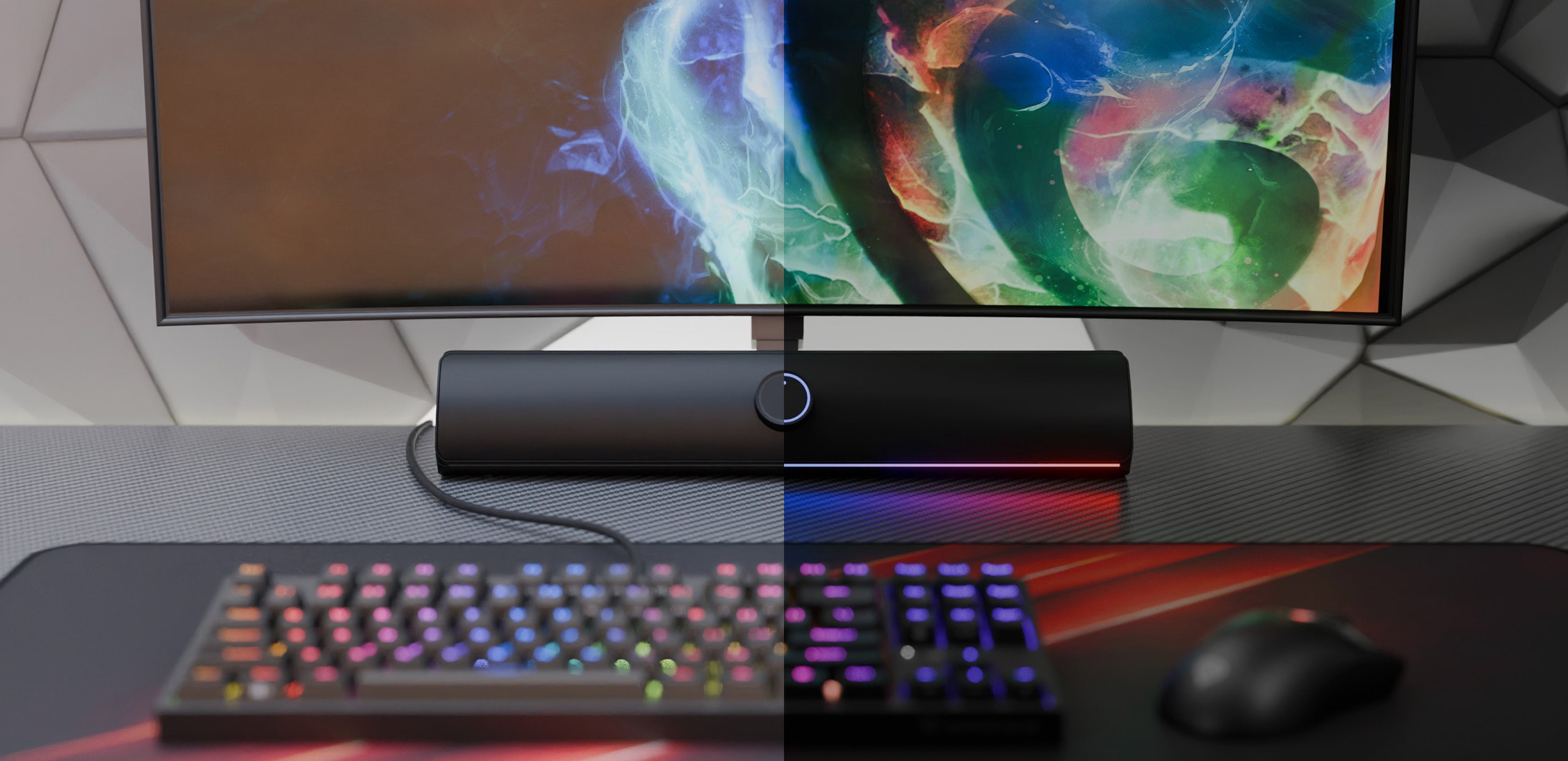 Barra de sonido Bluetooth negra colocada debajo de un monitor de colores, con un teclado y un ratón gaming RGB sobre un escritorio