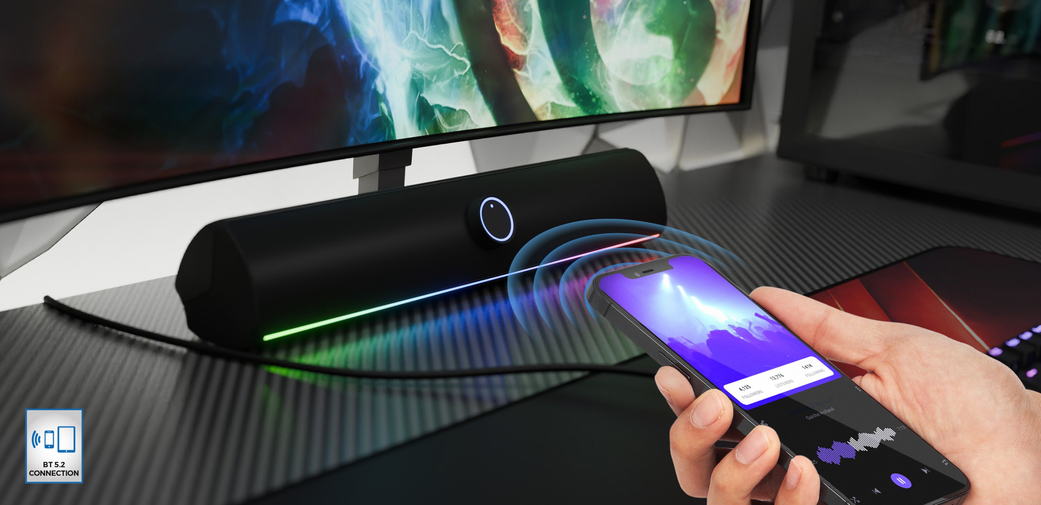 Barra de sonido Bluetooth en negro con iluminación LED, que se controla de forma inalámbrica mediante un smartphone en un escritorio