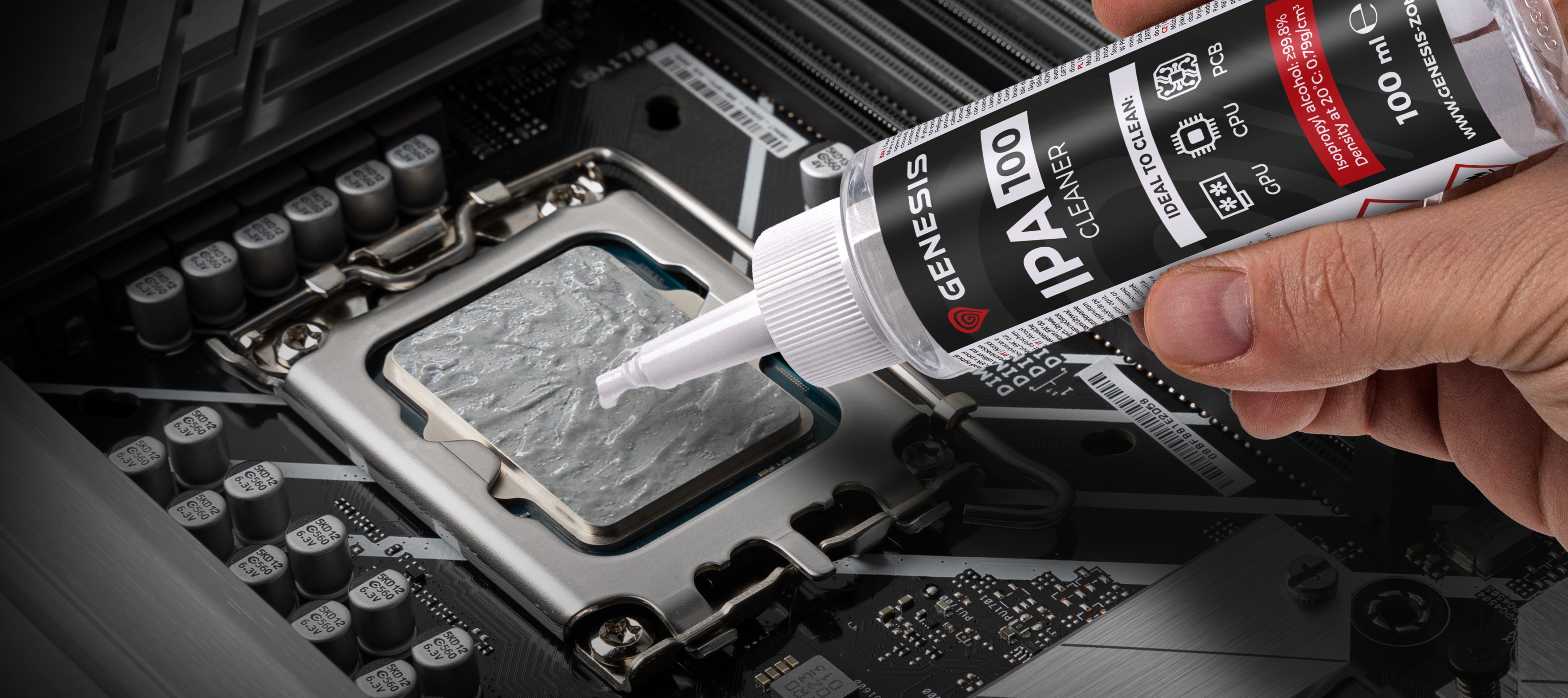 Mano sosteniendo una botella de limpiador Genesis IPA 100, aplicándola al zócalo de la CPU de un ordenador en una placa base