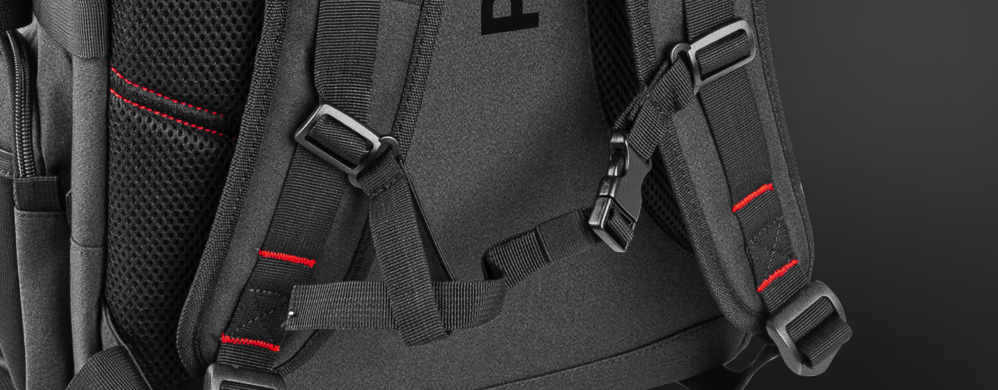Detalle de la mochila para portátil Genesis Pallad 550 con correas ajustables y detalles reflectantes sobre una superficie negra