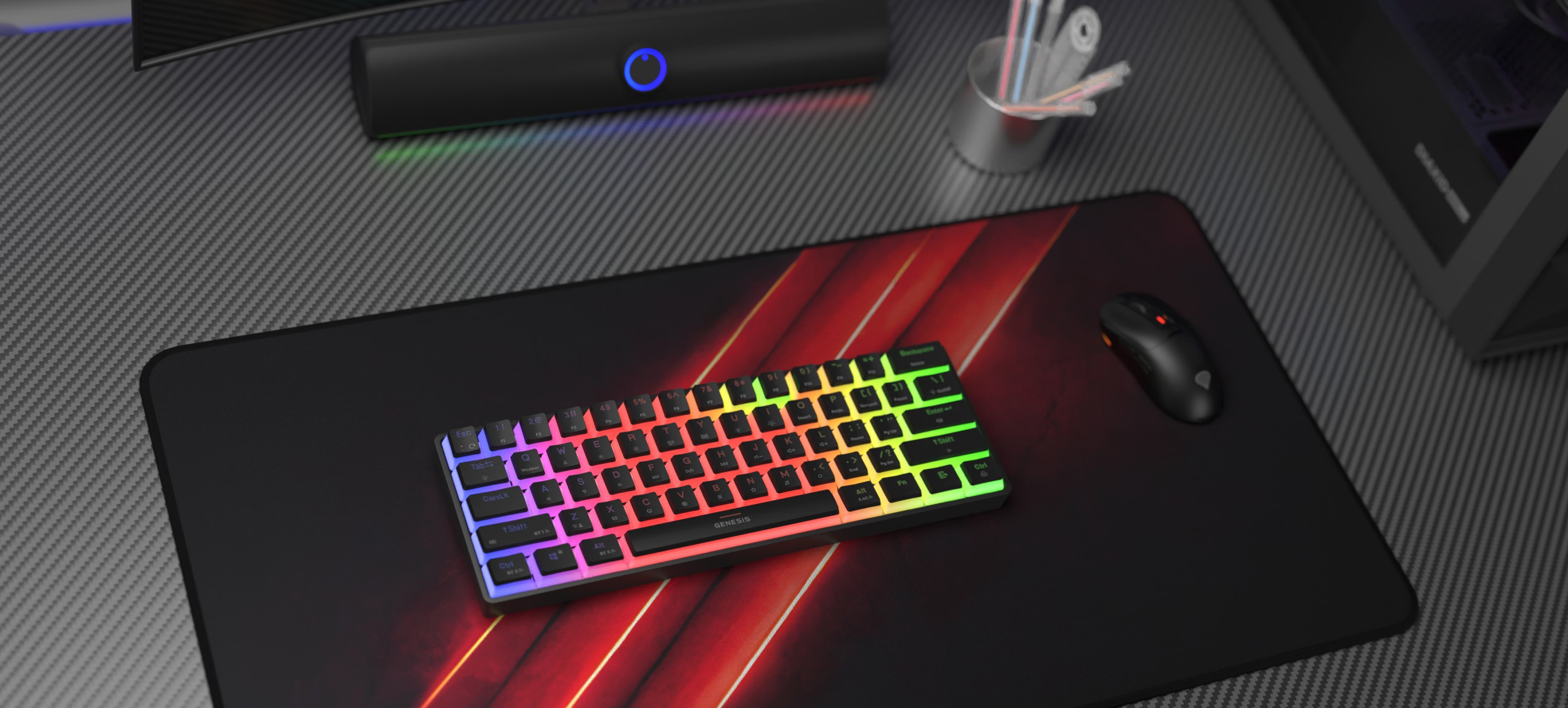 Teclado mecánico inalámbrico para juegos con iluminación RGB, colocado sobre una alfombrilla negra para juegos junto a un ratón para juegos y accesorios de escritorio