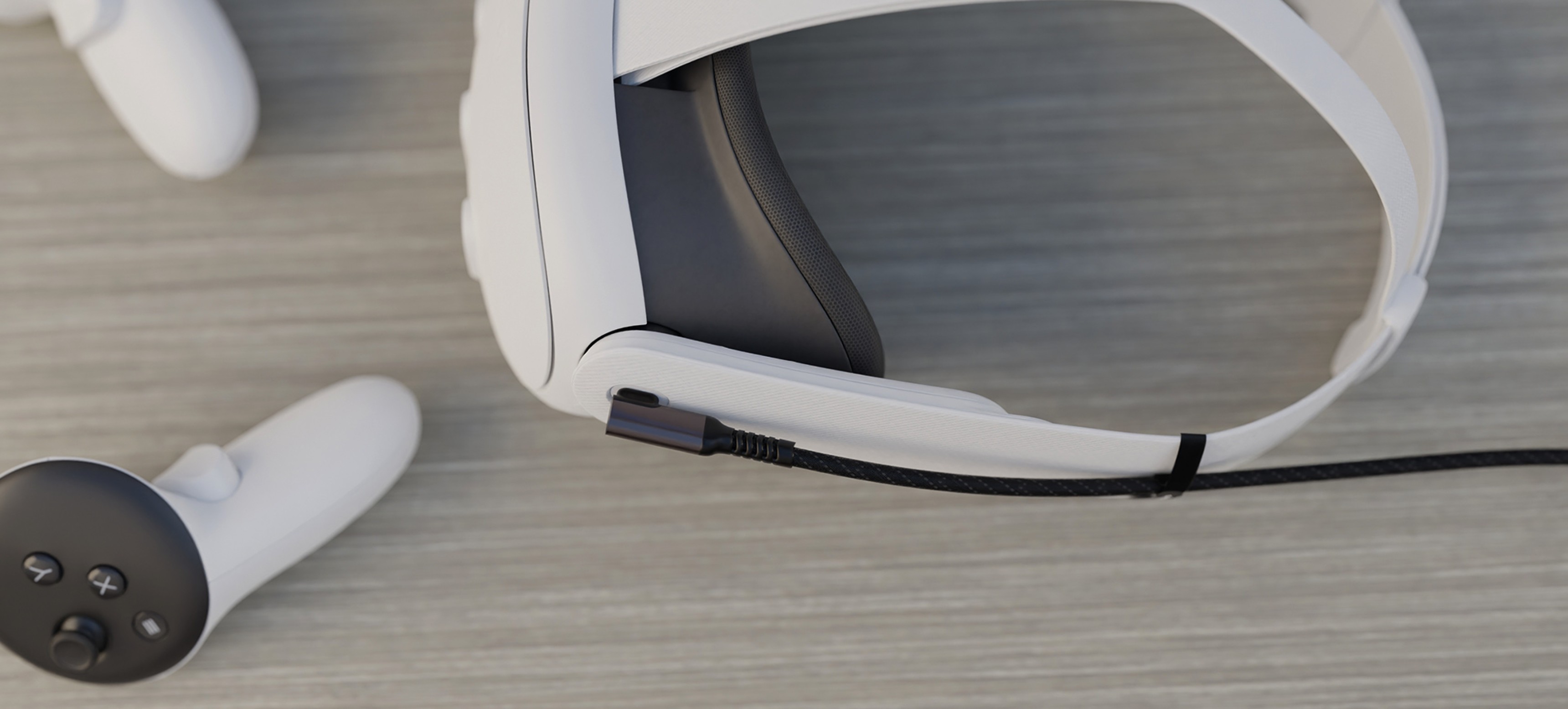 Cable USB-C macho-macho negro, de 3 m de longitud, colocado cerca de un casco de RV blanco y un mando sobre una superficie de madera