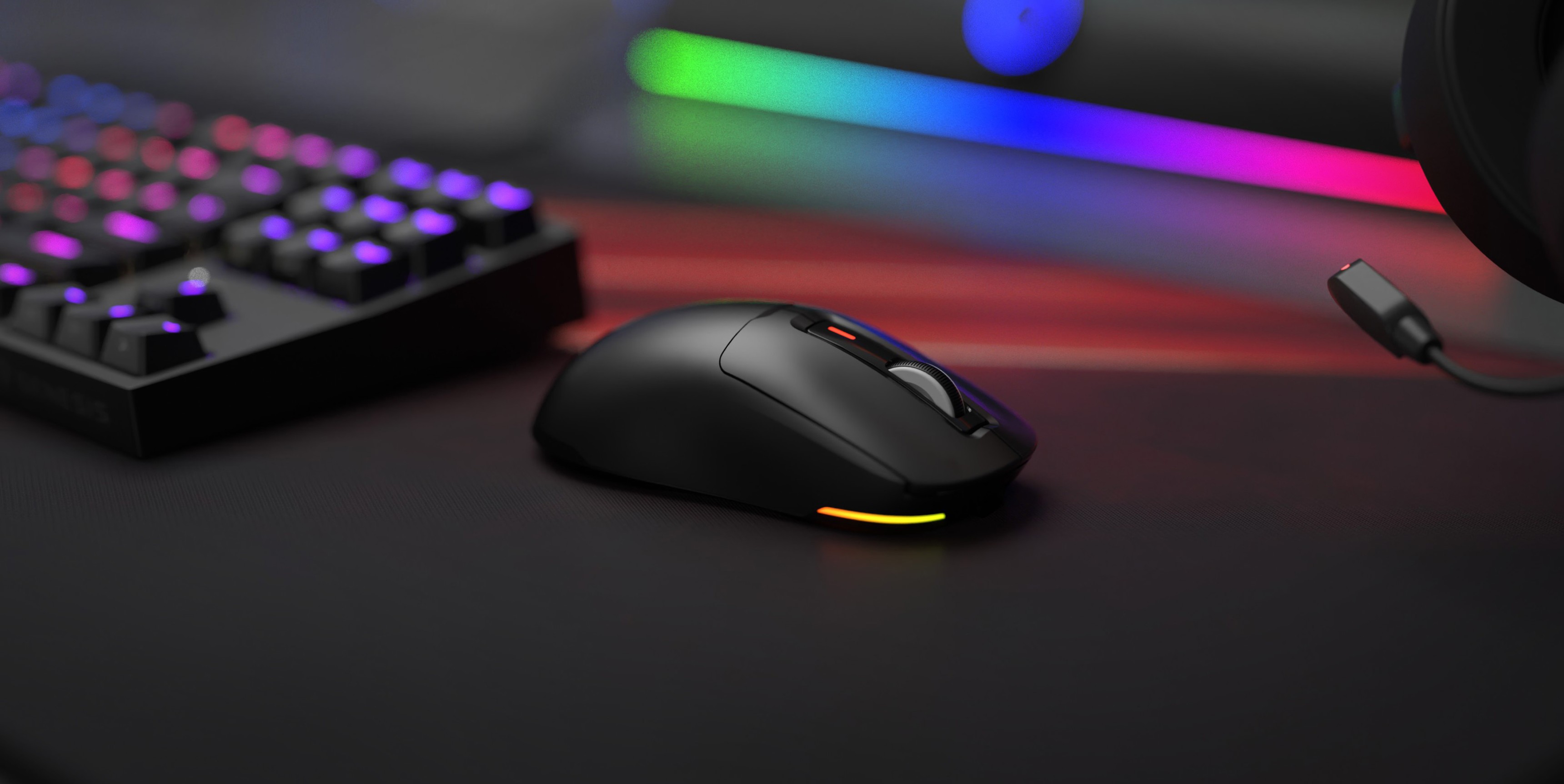 Ratón inalámbrico para juegos Genesis Zircon 660 negro con iluminación RGB, colocado sobre un elegante escritorio para juegos junto a un teclado mecánico