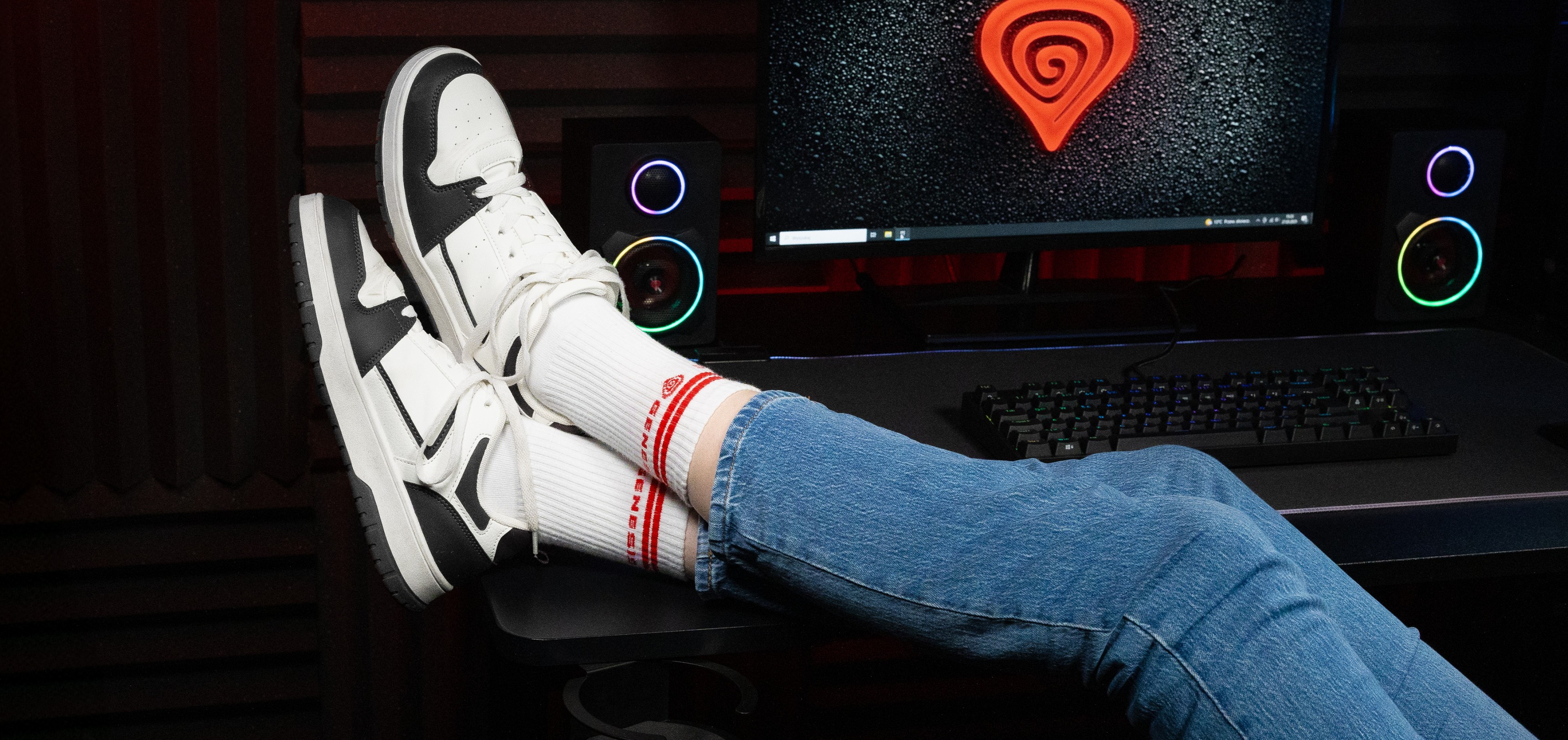 Calcetines deportivos en blanco con rayas rojas, llevados con elegantes zapatillas deportivas, y vaqueros azules sobre un fondo de ordenador