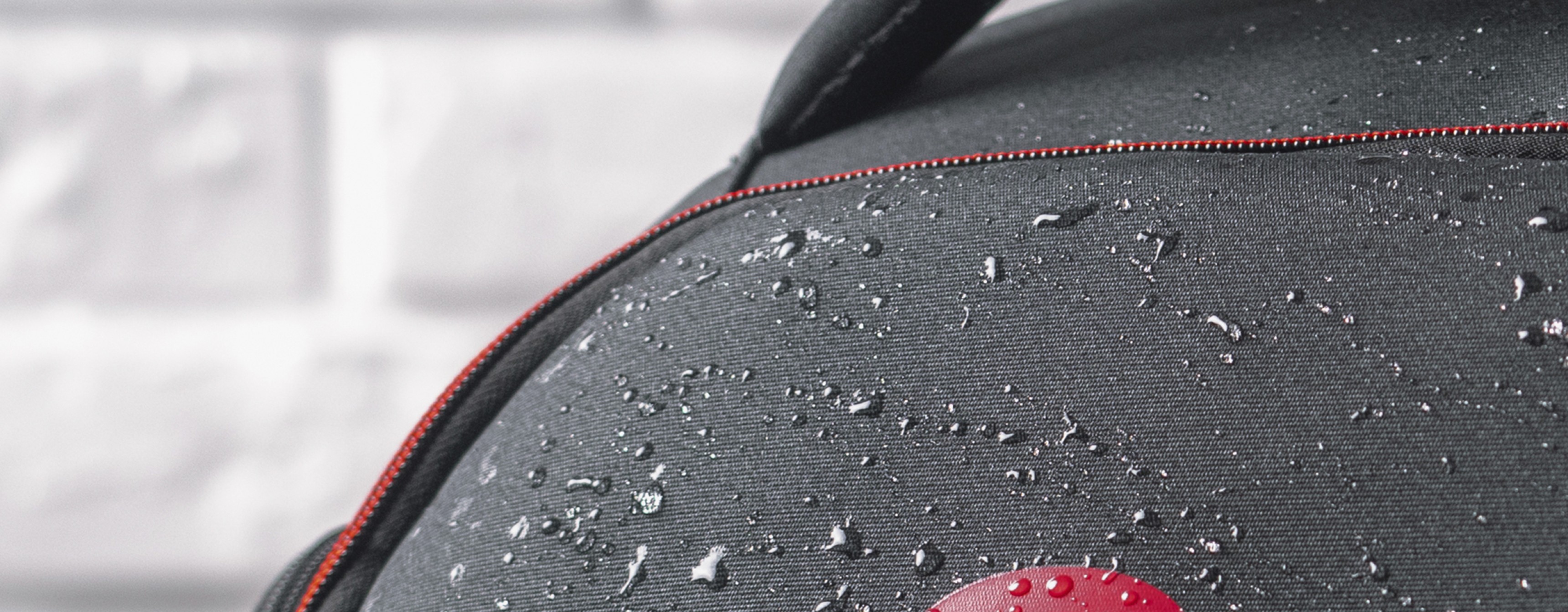 Mochila para portátil negra resistente al agua con detalles rojos, adecuada para portátiles de 15,6"/17,3", muestra gotas en el tejido