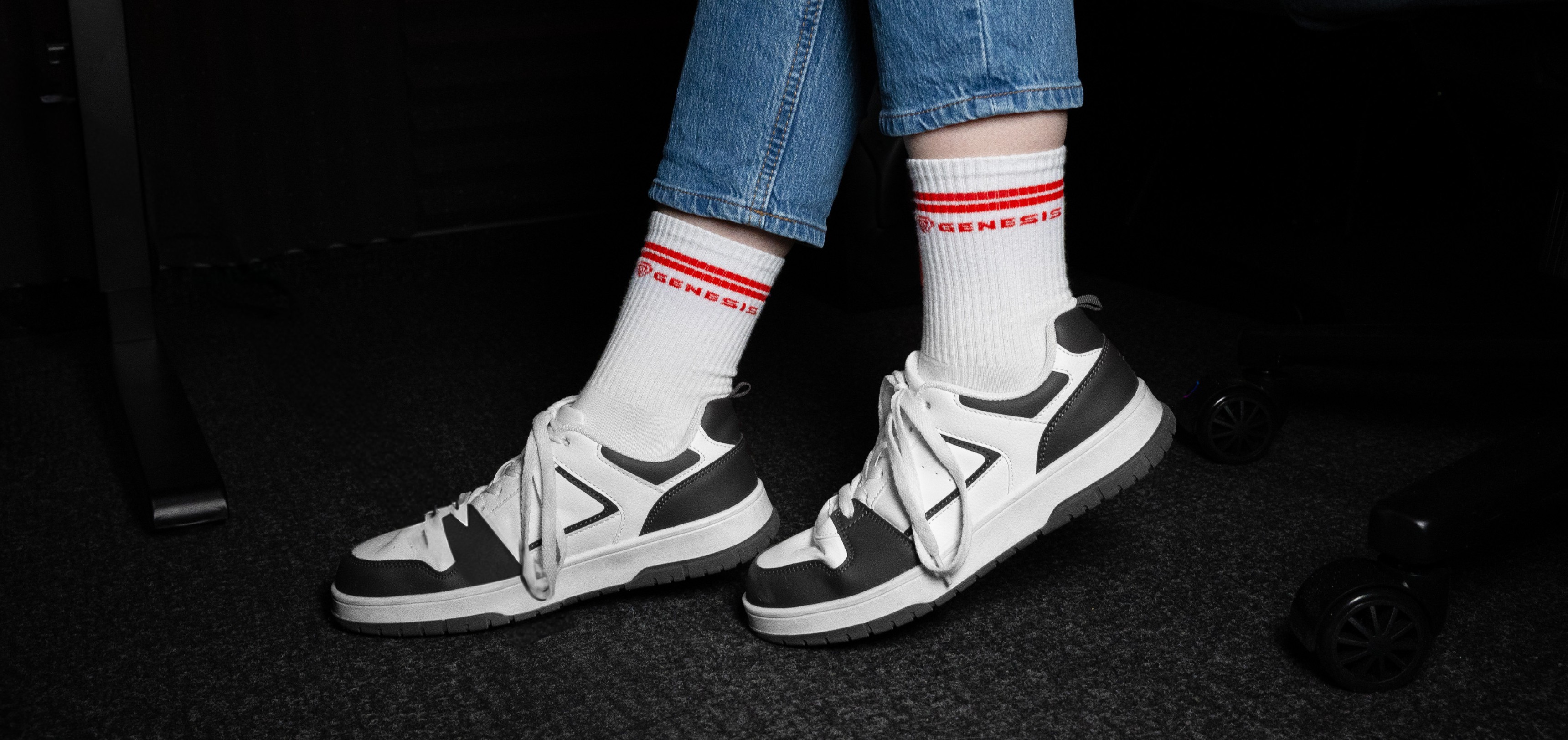 Calcetines deportivos blancos con rayas rojas, combinados con zapatillas grises y blancas y vaqueros azules
